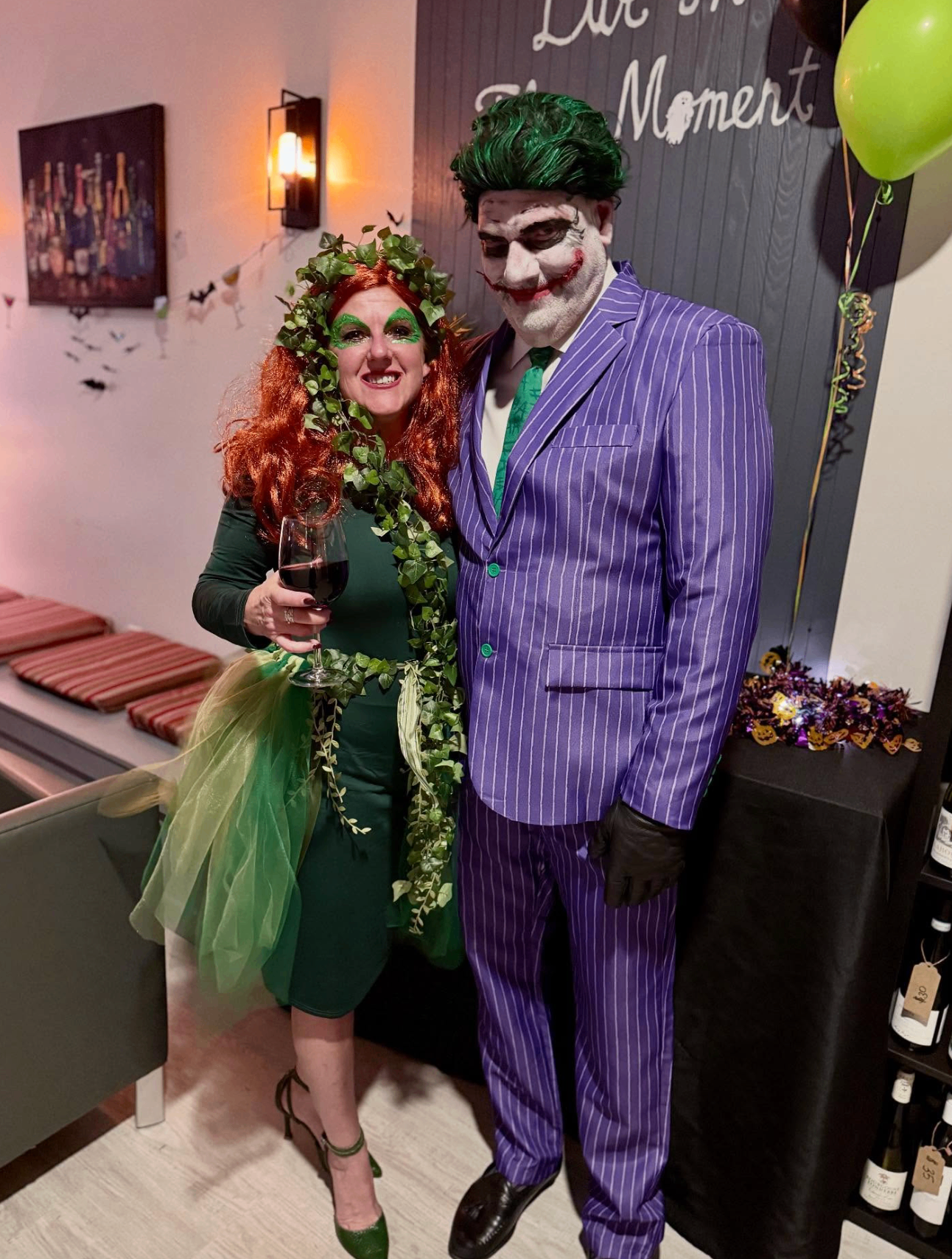 Couple dressed as Joker and Poison Ivy holding a glass of red wine