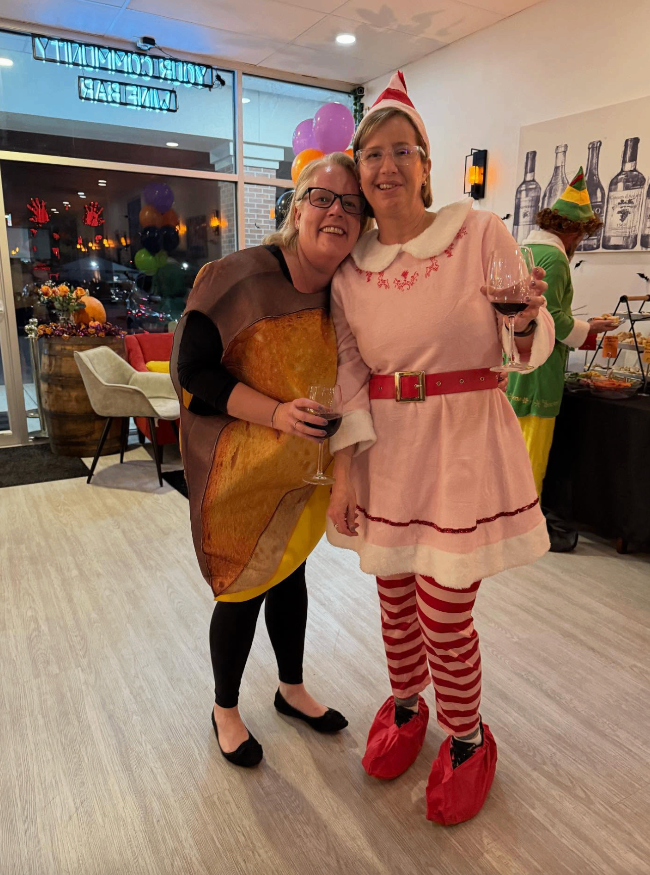 Guests dressed as a toast costume and an elf sharing wine at the Hallowine party