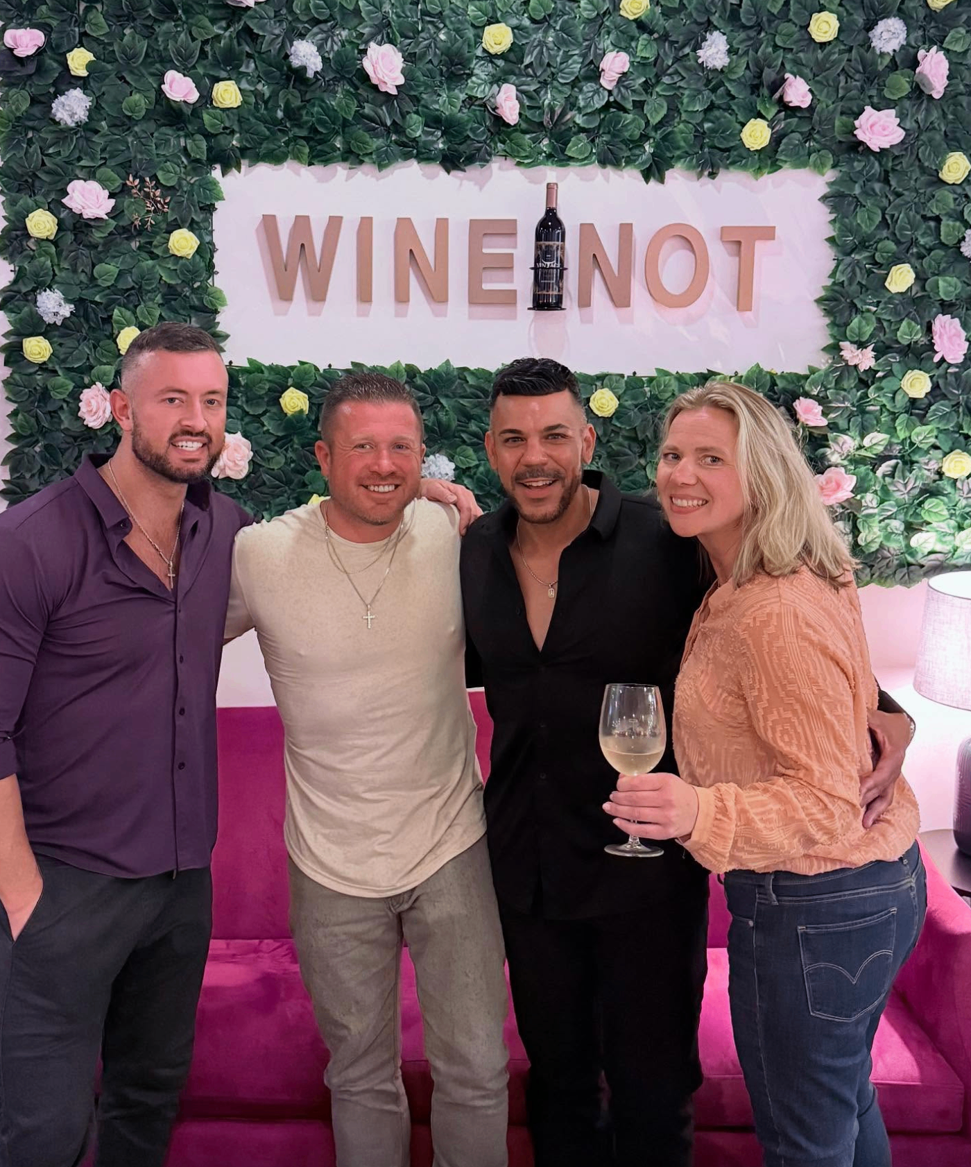 Four friends posing at the Wine Not floral wall