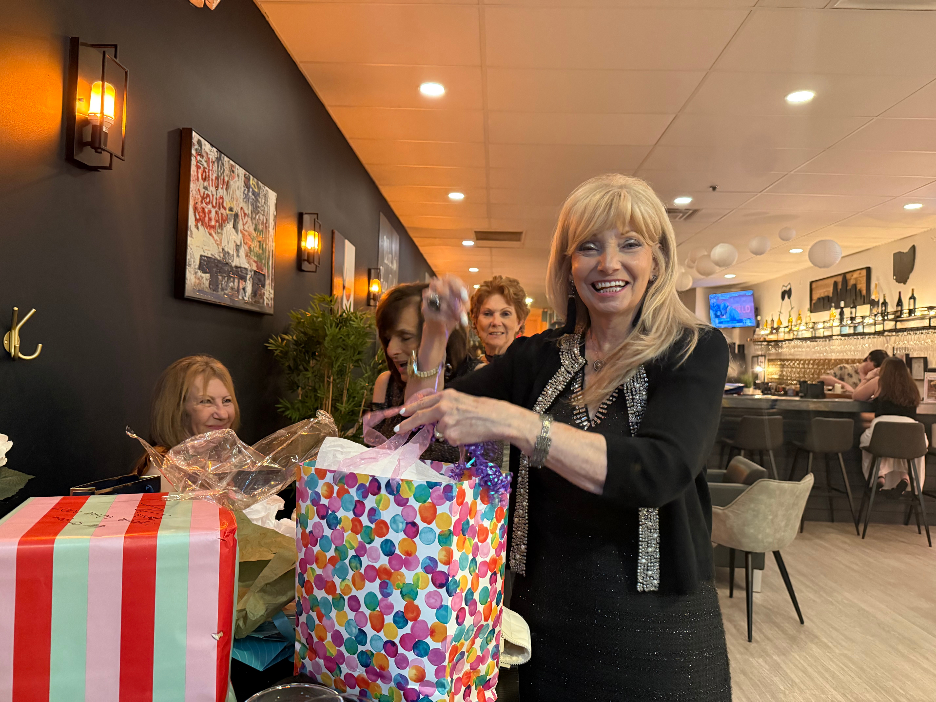 Guest opening gifts at a birthday celebration at WineNot Wine Bar
